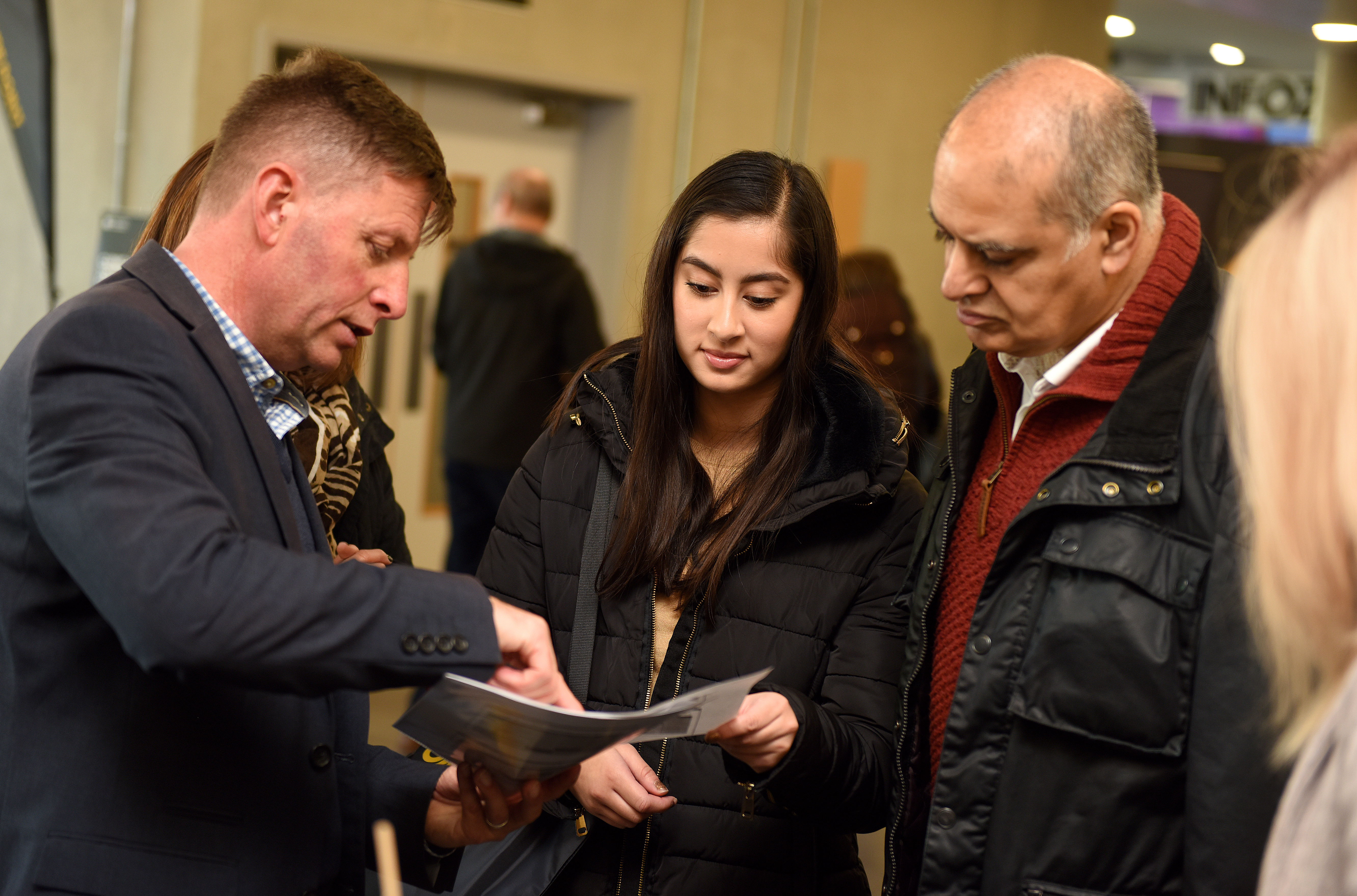 Parent and student talking with staff in a foyer